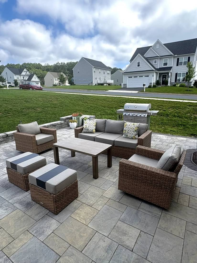Paver patio living set with wicker sofa, chairs, and a grill