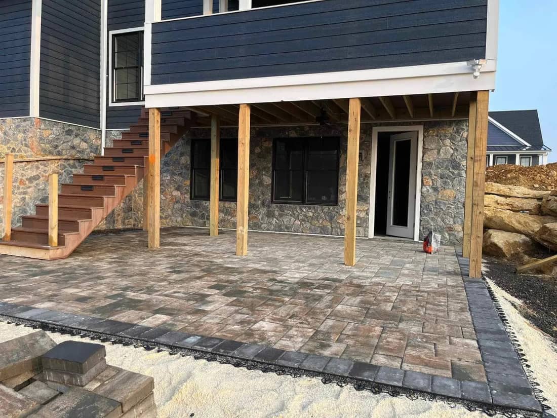Paver patio under a raised deck with stone veneer and border pavers